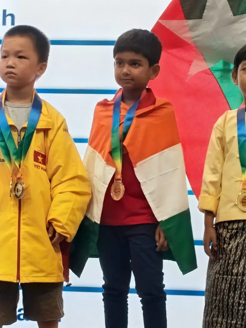 Riyaan Sidharth on the podium wrapped in the India flag with his ASEAN+ bronze medal